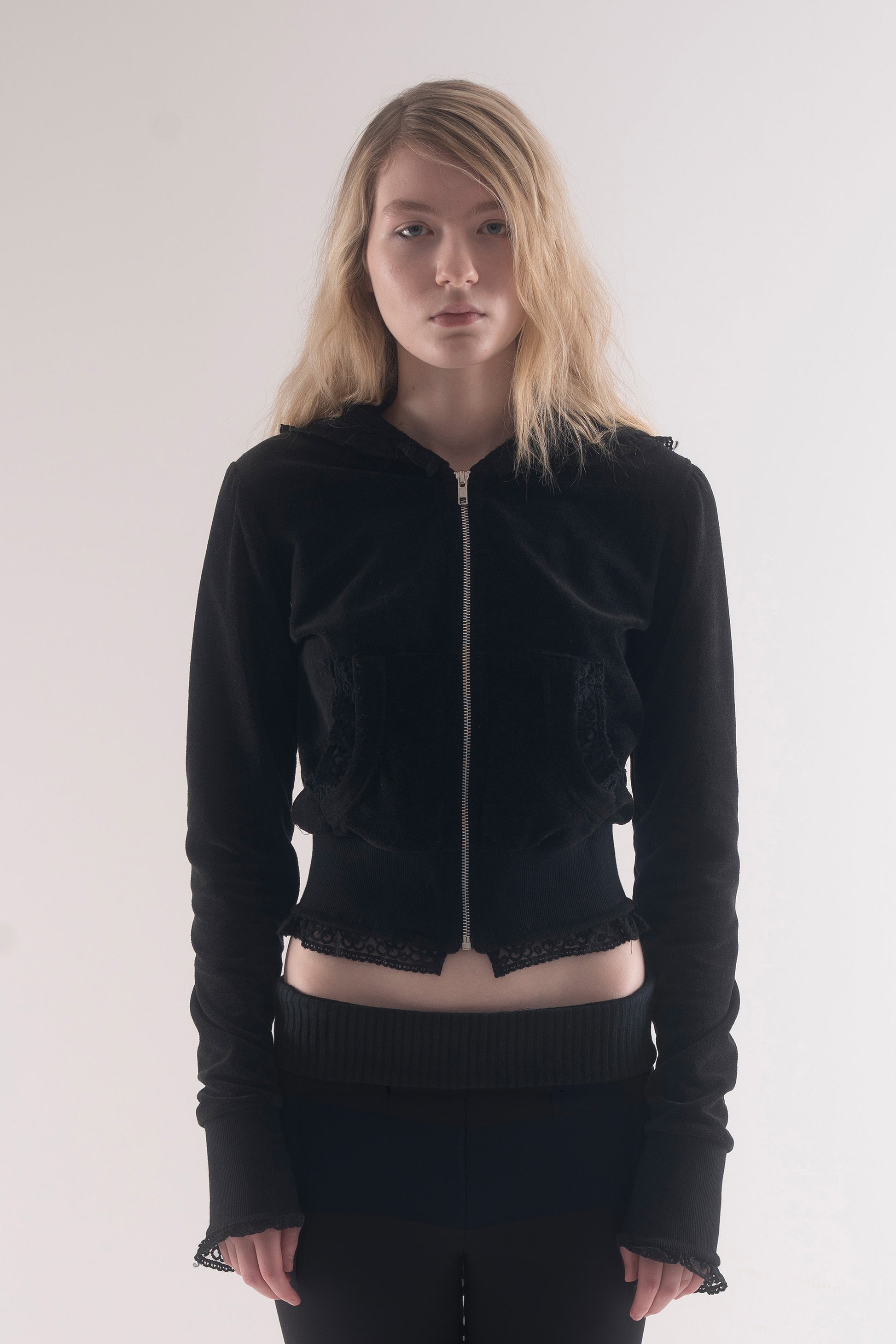 Person wearing a black zip-up hoodie and pants on a white background